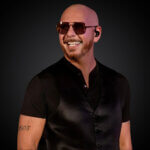 artist Pitbull in a black t shirt and sunglasses smiling